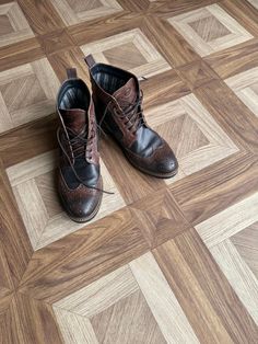 a pair of brown and black shoes sitting on top of a wooden floor next to each other