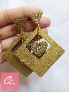 a pair of gold glittered heart shaped earrings with chains hanging from the front and back