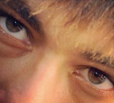 the eyes of a young man with long hair are shown in this close up photo