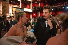 a man in a tuxedo standing next to a woman in a dress at an event