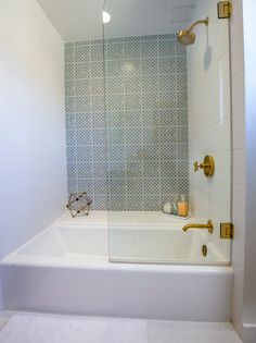 a white bath tub sitting inside of a bathroom next to a shower head and faucet