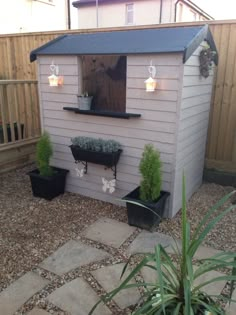 a small garden shed with potted plants and lights