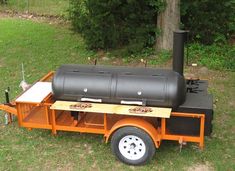 an outdoor bbq grill on the back of a trailer parked in a grassy area