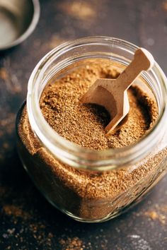 a glass jar filled with spices on top of a table