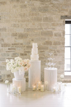 three tiered white wedding cake stands next to each other with candles in front of them