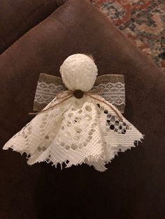 an angel made out of doily on top of a brown chair with a bow