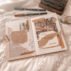 an open book sitting on top of a bed next to some scissors and other items