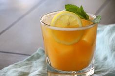 a glass filled with lemonade and mint on top of a blue towel next to a wooden table