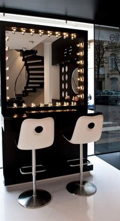 a room with two chairs and a mirror on the wall next to it is decorated with lights