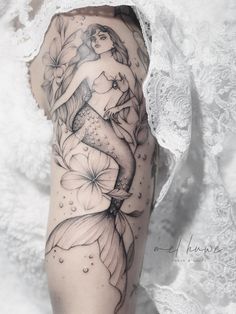 a woman's arm with flowers and a mermaid tattoo on the left side of her body