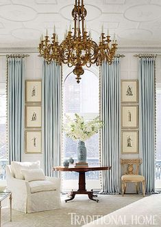 a living room filled with furniture and a chandelier hanging from the ceiling next to a window