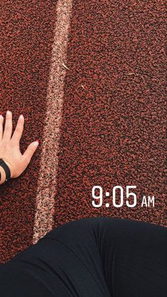 a woman's hand on the ground next to a red wall with white lines