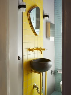 a sink and mirror in a bathroom with yellow tiles on the walls, along with other accessories