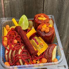 a plastic container filled with food next to a piece of fruit and a slice of lime