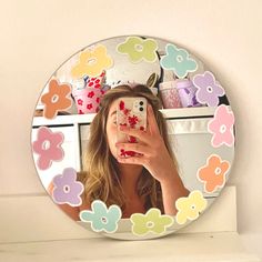 a woman taking a selfie in front of a mirror with flowers painted on it