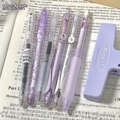 four pens are sitting next to each other on an open book with chinese characters in the background