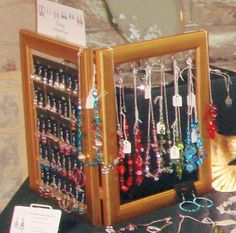 a display case filled with lots of necklaces and earrings on top of a table