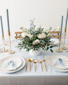 a table set with plates, silverware and flowers