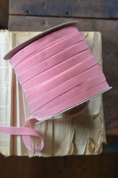 a roll of pink ribbon sitting on top of an open book