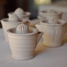 four white ceramic cups sitting on top of a table