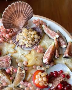 an assortment of fruits and vegetables on a plate with seashells, starfish