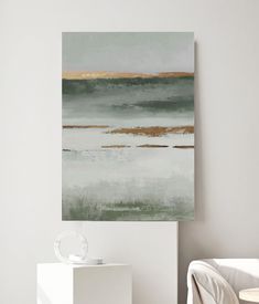 an abstract painting hangs on the wall above a white chair