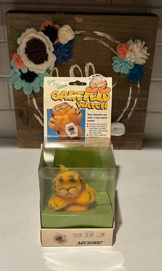 a yellow stuffed animal sitting inside of a box on top of a white countertop