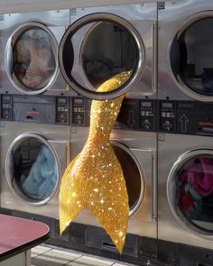 a yellow ribbon hanging from the side of a dryer door in front of washing machines