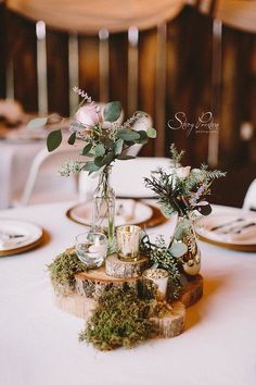 two vases filled with flowers and greenery sit on top of a wooden table