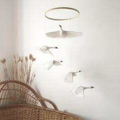 three seagulls are flying in the air near a wicker chair and white wall