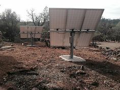 two solar panels sitting on top of a dirt field