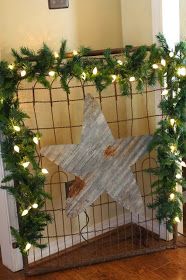 a wooden star surrounded by greenery in front of a fence with lights on it