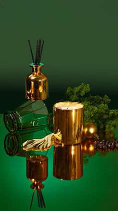 three golden candles are sitting next to each other on a green surface with trees in the background