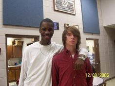 two young men standing next to each other in a room with blue and white walls