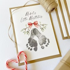 a christmas card with a hand and foot print on it next to candy canes