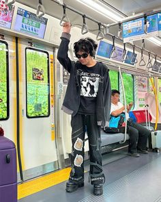 a man standing on a subway train with his arms in the air and wearing black boots