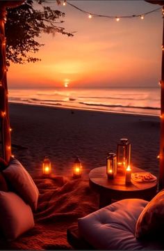 candles are lit up on the beach at sunset with an ocean view in the background