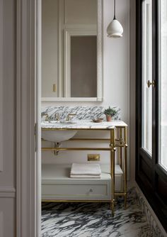 a bathroom with marble counter tops and gold fixtures, along with a mirror above the sink