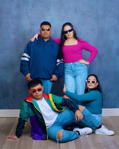 three people are posing for a photo in front of a blue wall and wood floor