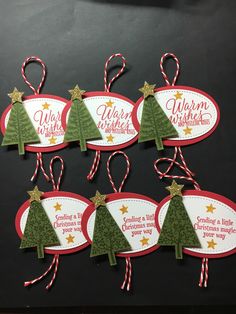 six christmas tree tags hanging on a black surface