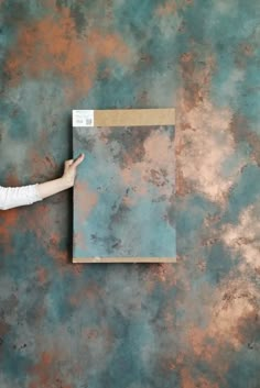 a woman pointing at a piece of paper on a wall with blue and brown paint