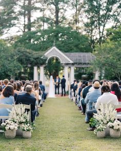 an outdoor wedding ceremony with white flowers and greenery on the aisle, surrounded by trees