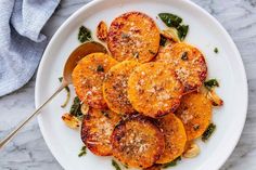 a white plate topped with sliced oranges covered in parmesan cheese and seasoning