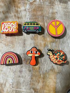 six magnets with different designs on them sitting on top of a piece of wood