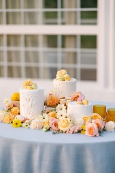 the wedding cake is surrounded by flowers and lemons on the table outside in front of an open window