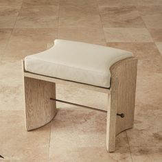 a wooden bench sitting on top of a tile floor next to a tiled floor with a white cushion