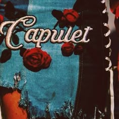 a woman's jean skirt with roses on it and the word capule written in white letters