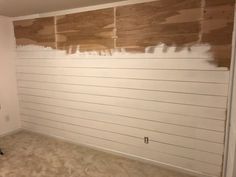 a room that has been painted white with wood planks on the wall behind it