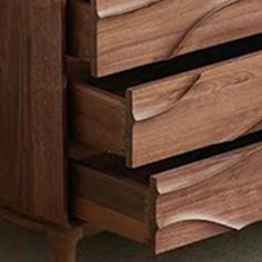 a close up of a wooden dresser with three drawers and one drawer open to show the wood grain