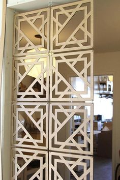 a room divider made out of white wood with geometric designs on the doors and sides